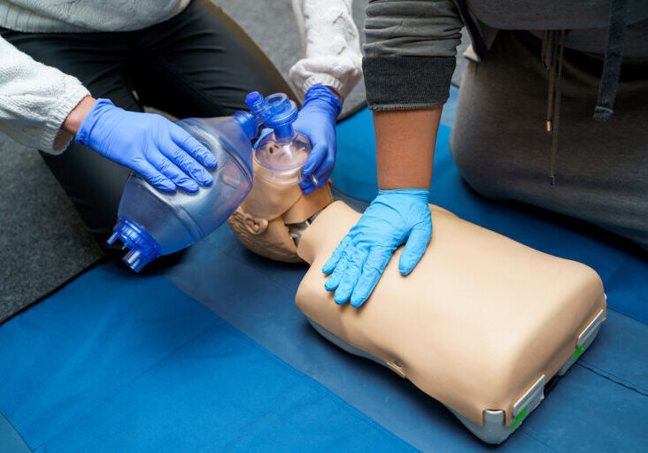 Man using CPR technique on dummy in first aid class. Oxygen mask on medical doll. Stock photo